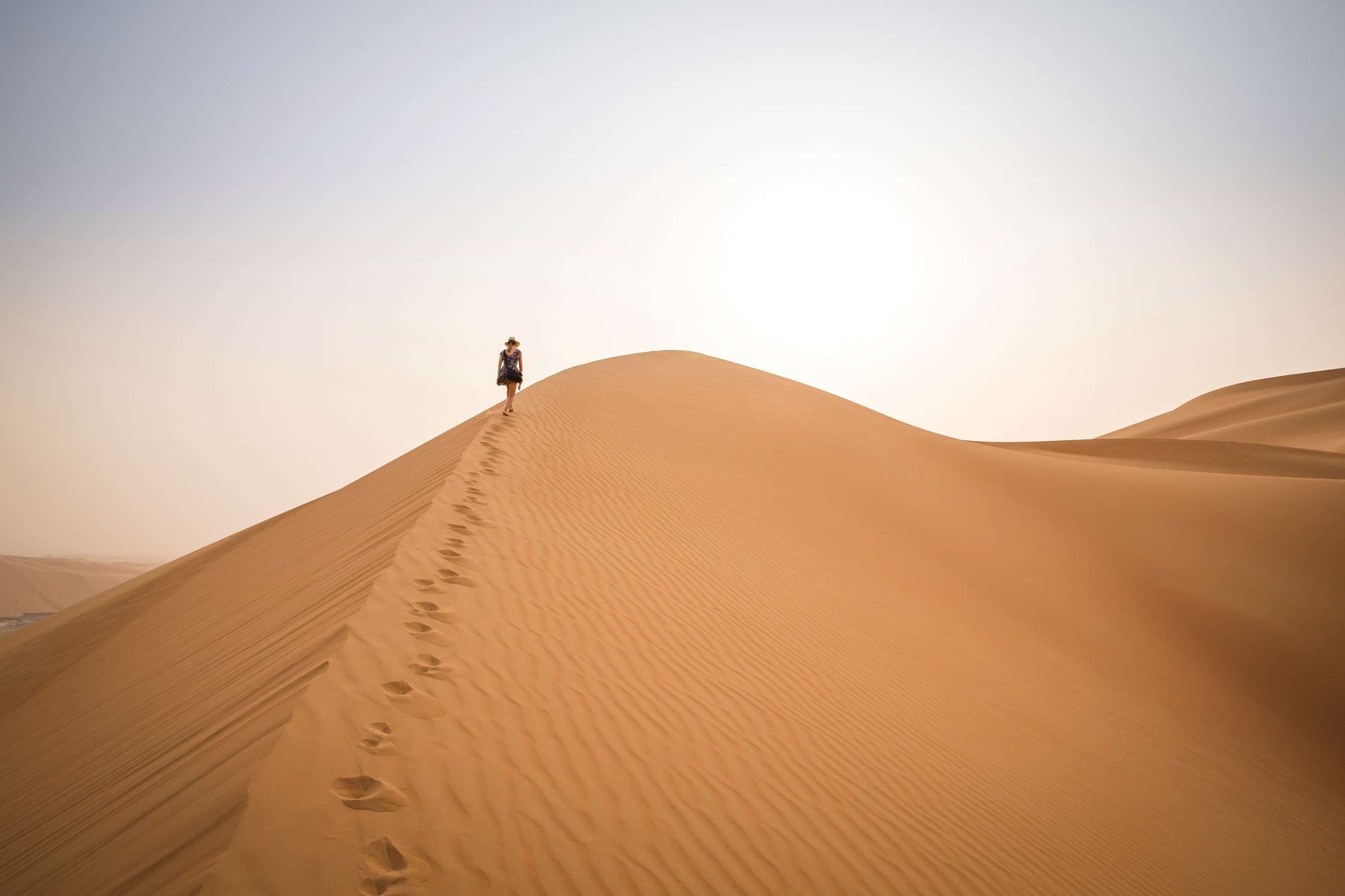 Figure walking up a sand dune in Rub al Khali Desert at the Empty Quarter, in Abu Dhabi