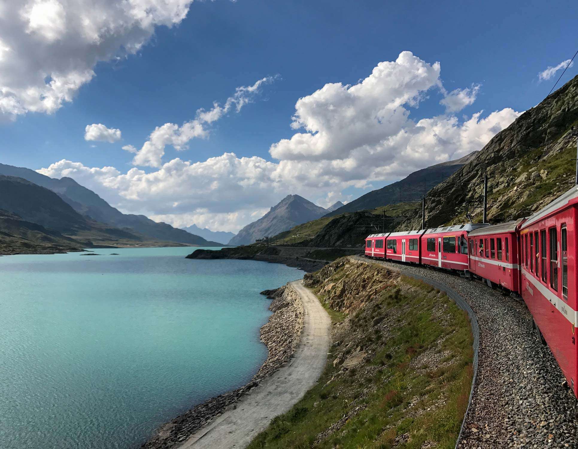 Red train traveling near a swiss lake