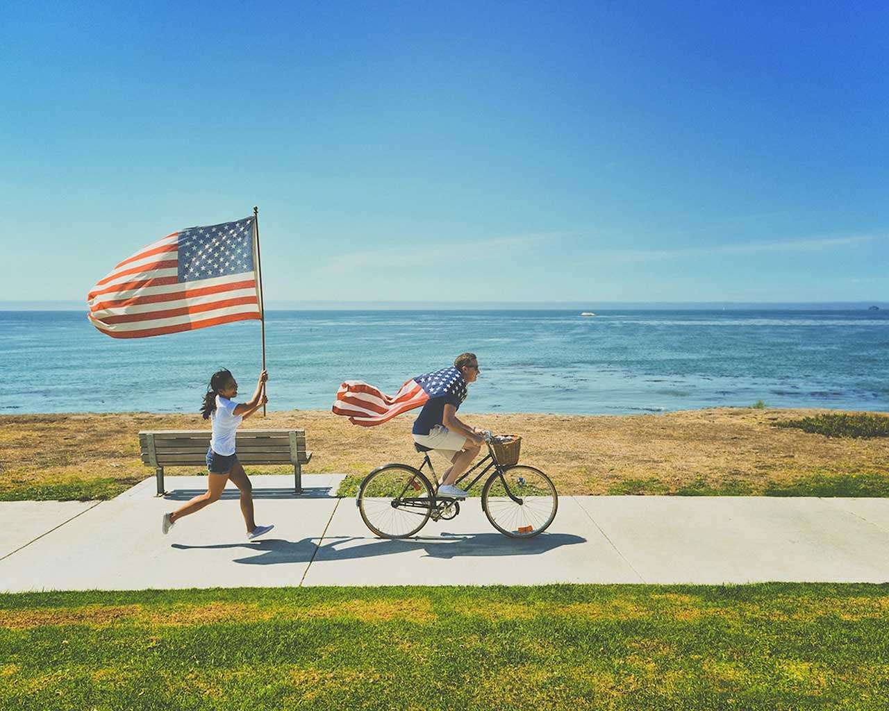 Man riding bike and woman running holding flag of USA