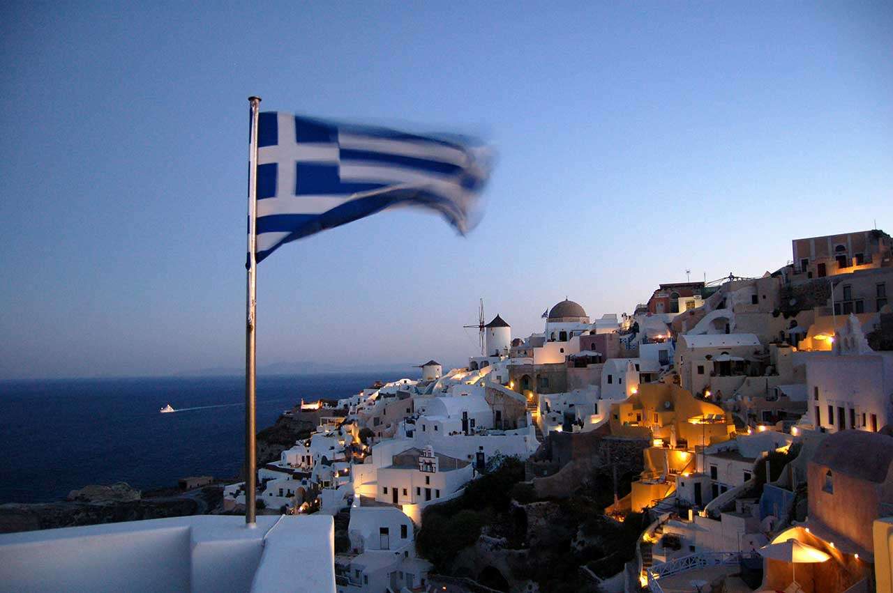Flag of Greece waving at pole at Santorini in Greece 