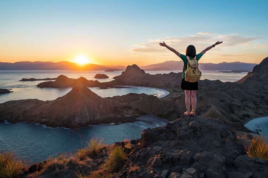 A woman standing on the peak of Padar Island in sunset time, Komodo Nation Park, Indonesia.
