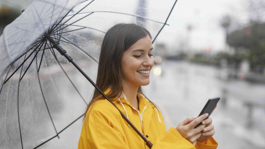 Woman with umbrella using mobile phone