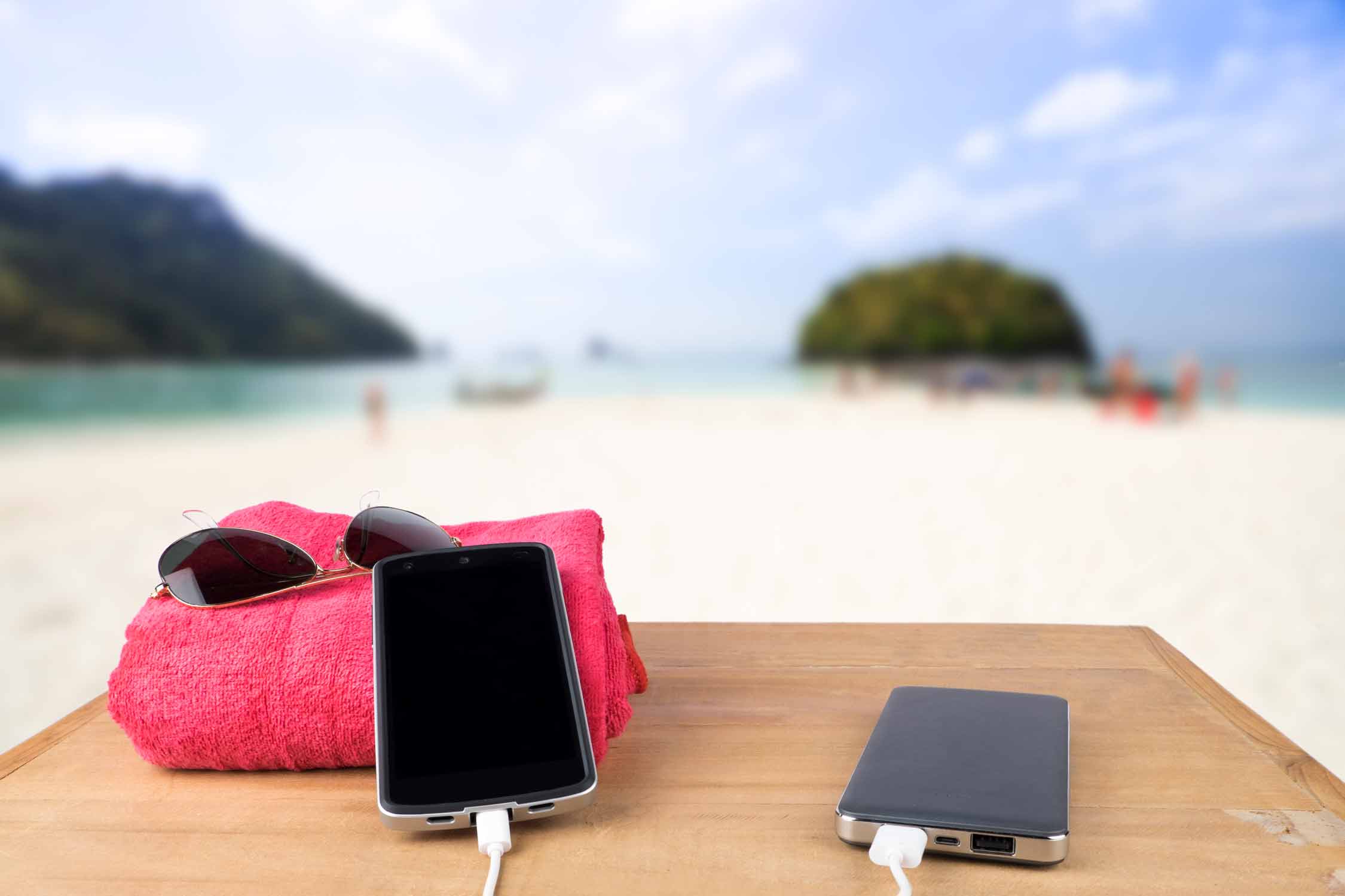 Two smartphones charging on the beach