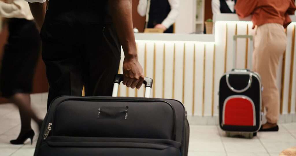 Businessman carrying trolley arriving hotel reception front desk