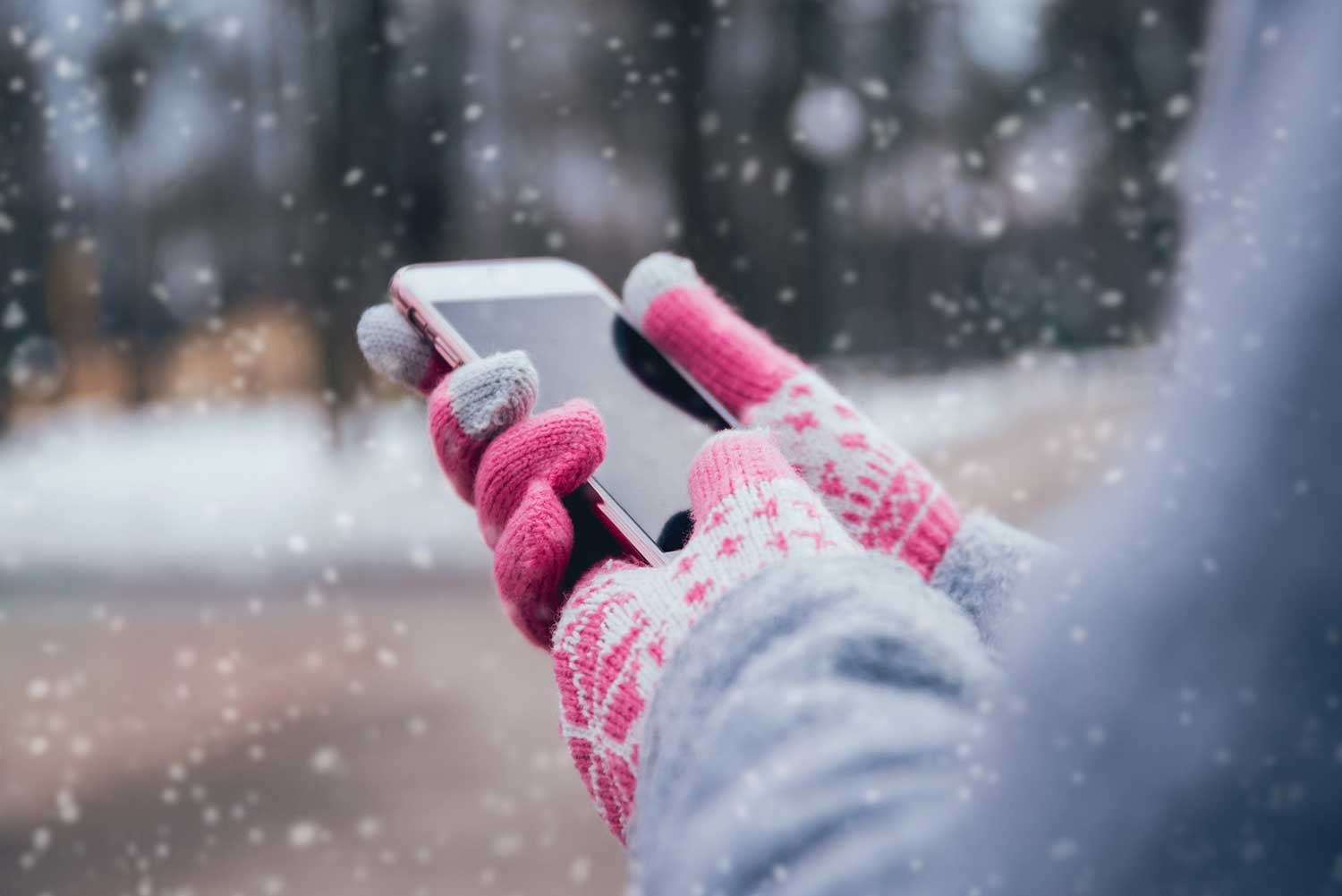 Donna che usa lo smartphone in inverno con guanti per schermi touch