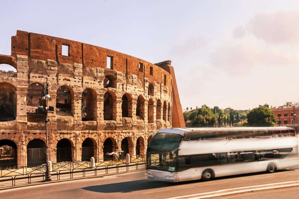 Bus turistico bianco a Roma con il Colosseo in una mattina di sole