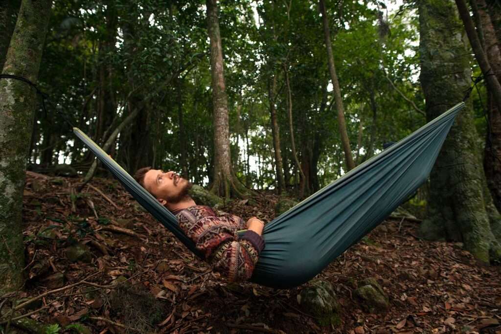 Adventurous man relaxing in a portable hammock