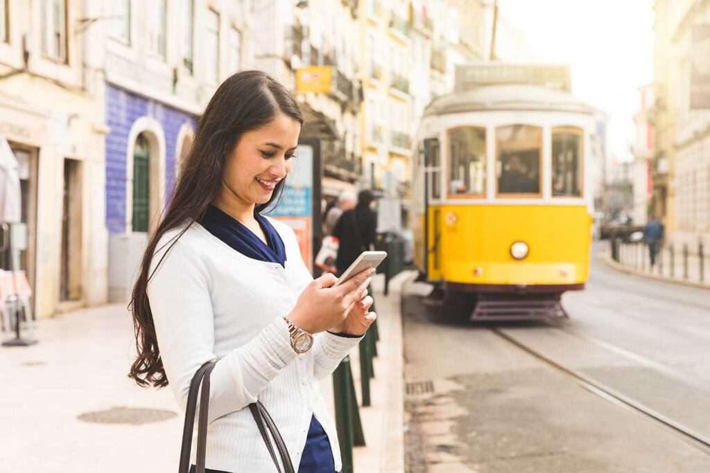 Tourist in Lisbon checking tram schedules on her smartphone.
