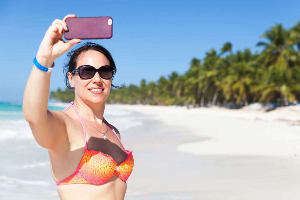 Smiling young woman makes a video call on a beach in the Dominican Republic