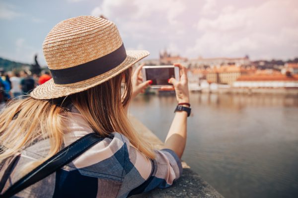 Young woman happy with backpack tourist taking selfie photo camera on Charles Bridge in Prague, Czech Republic. Concept travel.